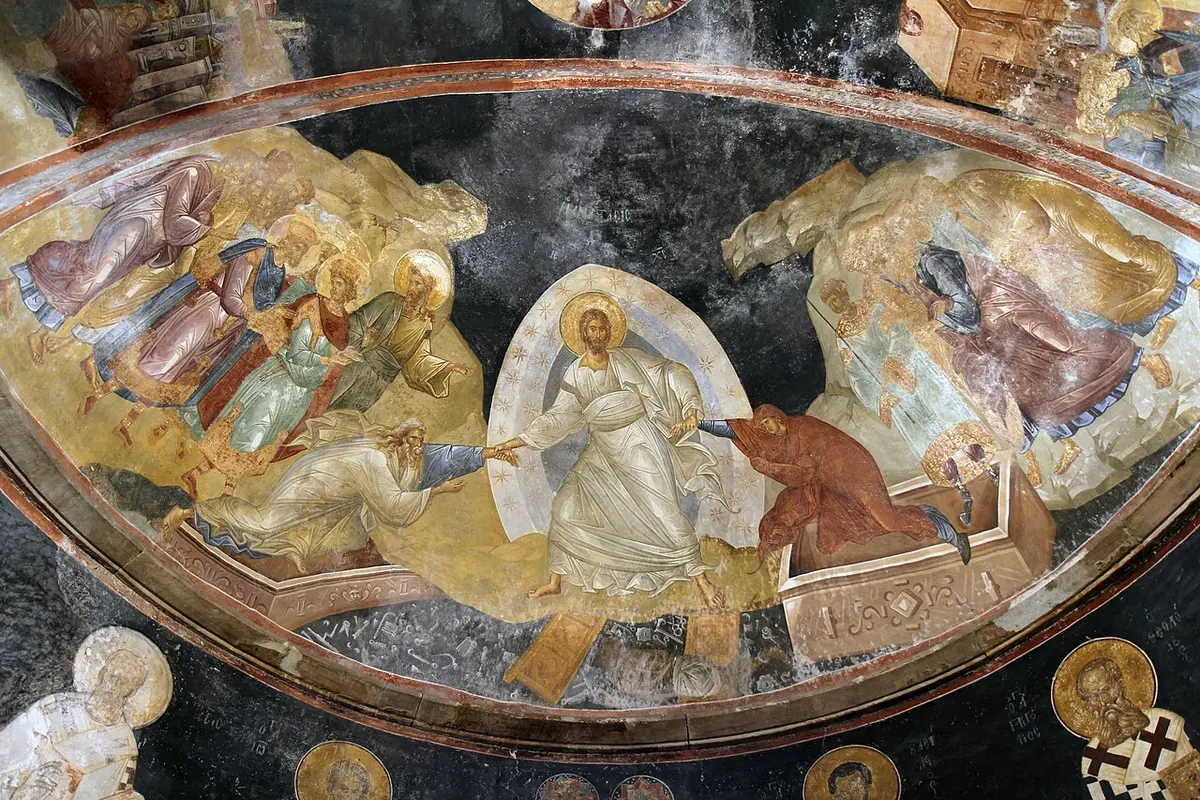 Fresco in a half dome of Christ in white pulling Adam and Eve from their tombs