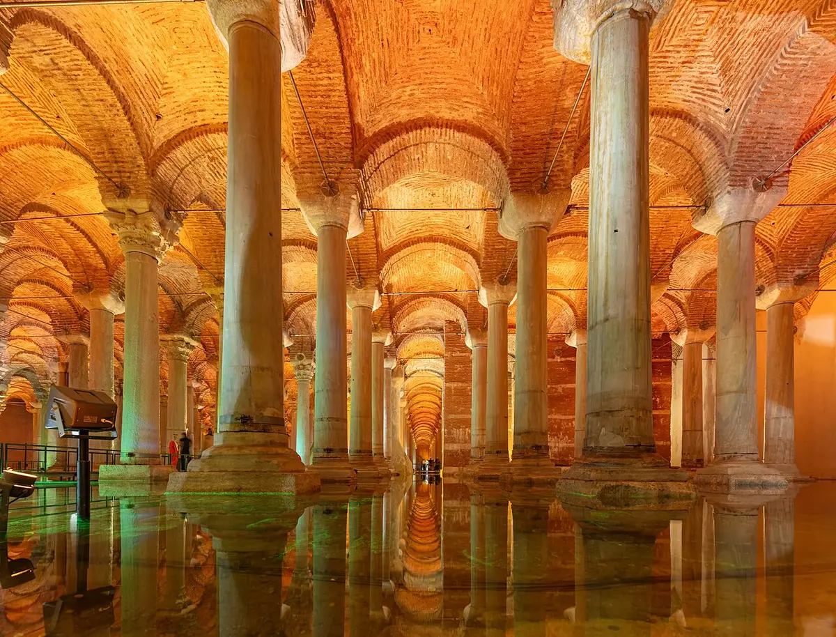 Rows of marble columns rising from shallow water under the lit brick vaults of the Basilica Cistern