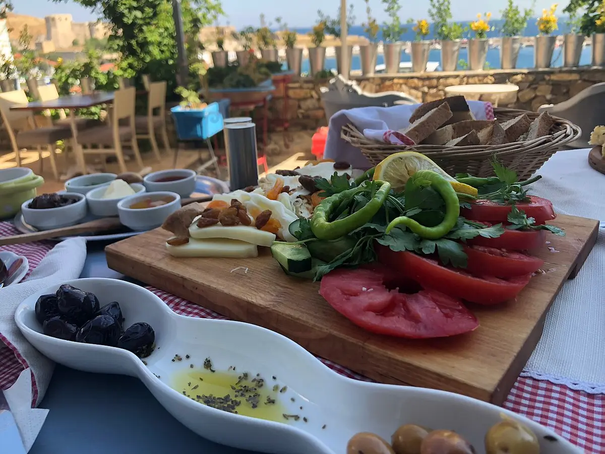 A Turkish breakfast on a terrace table: tomatoes, peppers, olives, cheese, bread and olive oil