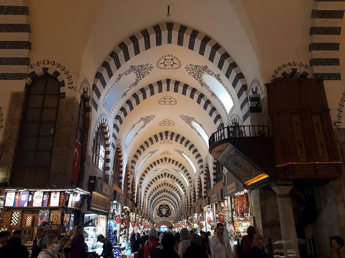 A long vaulted street of the Grand Bazaar, striped arches running into the distance above the shops