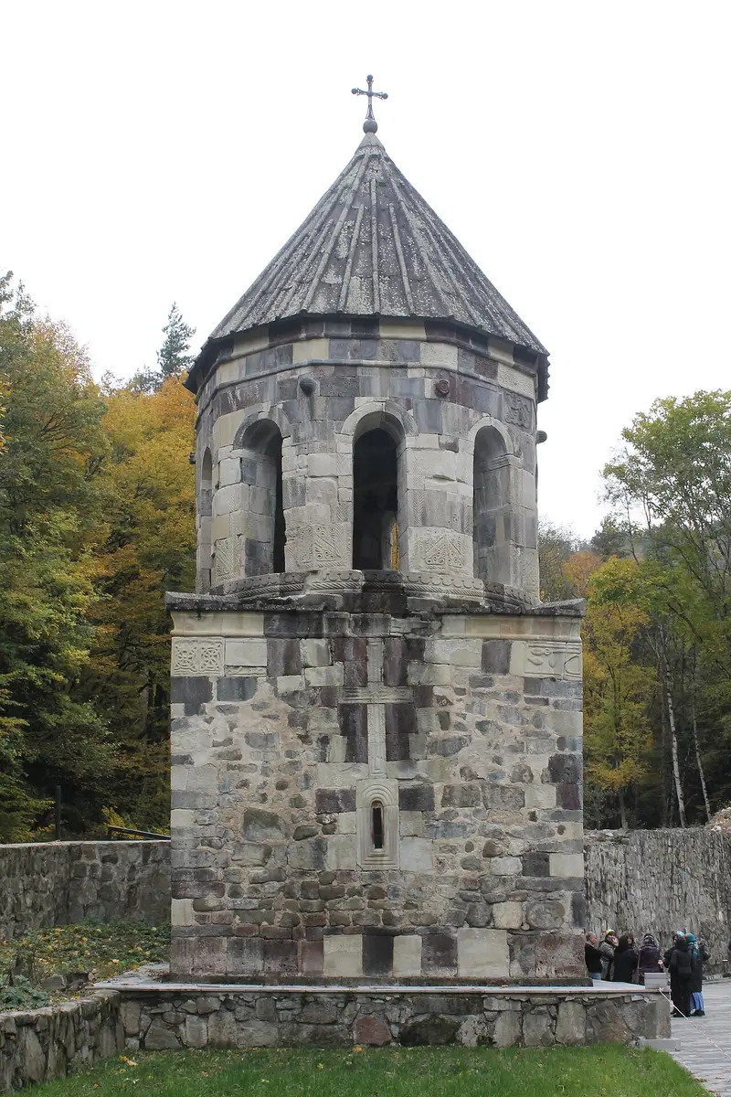 The stone bell tower of the Green Monastery among autumn trees