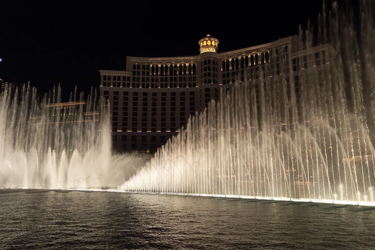 Rows of water jets rising in a long arc on the lake in front of the Bellagio hotel at night