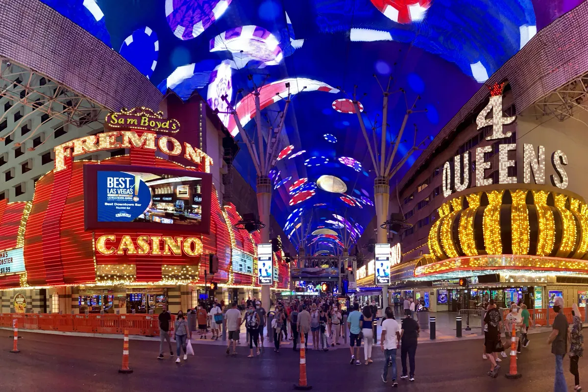 Neon casino fronts reading Fremont and 4 Queens under the lit canopy of the Fremont Street Experience at night