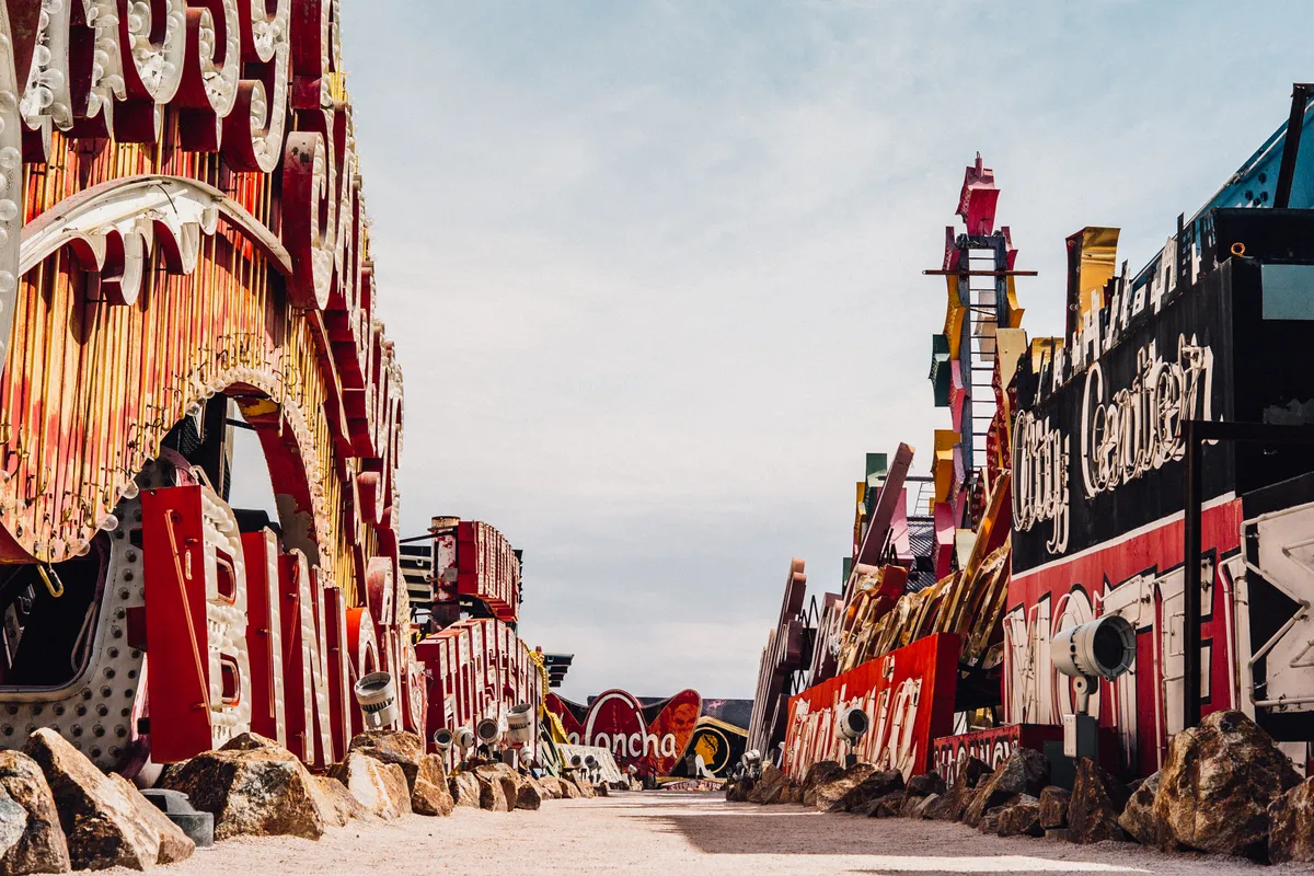 Giant old casino and motel signs lining both sides of a gravel path in the Neon Boneyard
