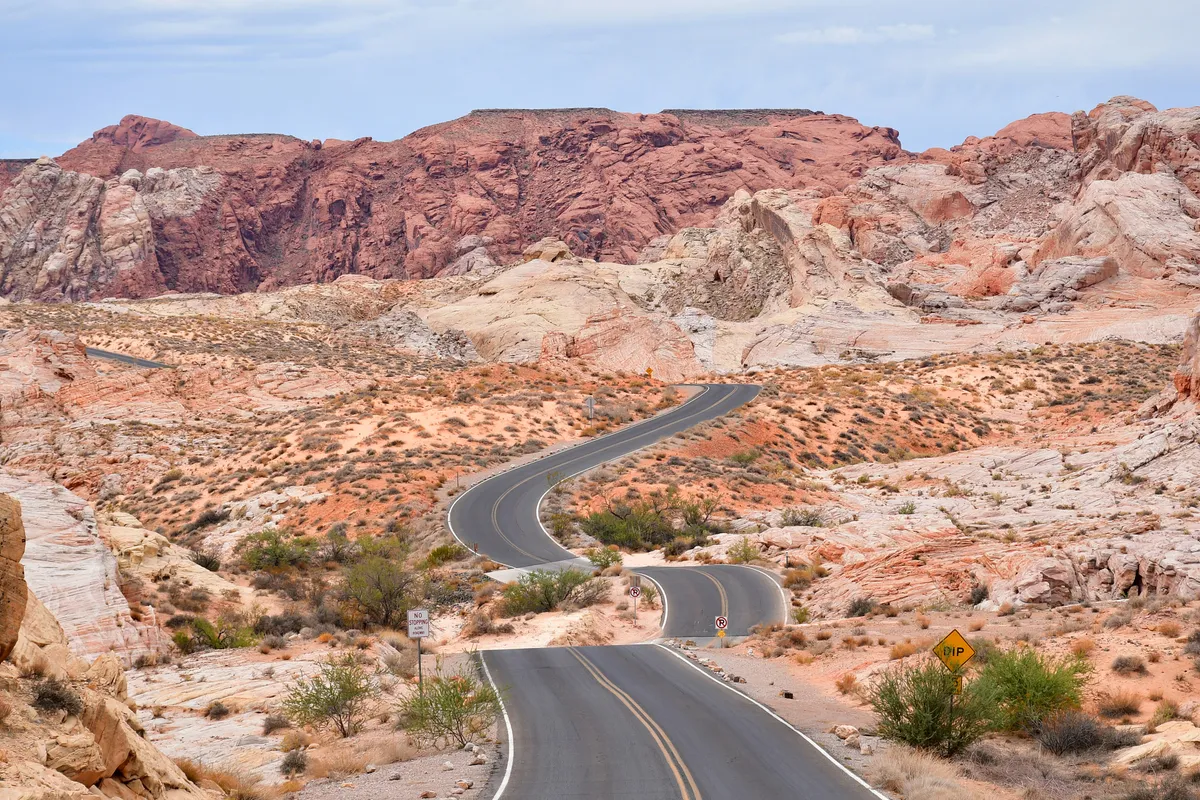 A road winding through red and white sandstone hills in the desert