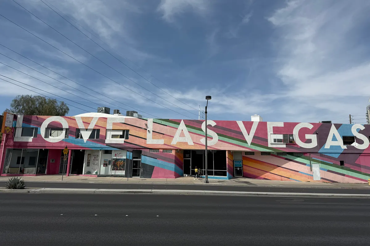 A low pink building painted with rainbow stripes and the giant white words LOVE LAS VEGAS, under a blue sky