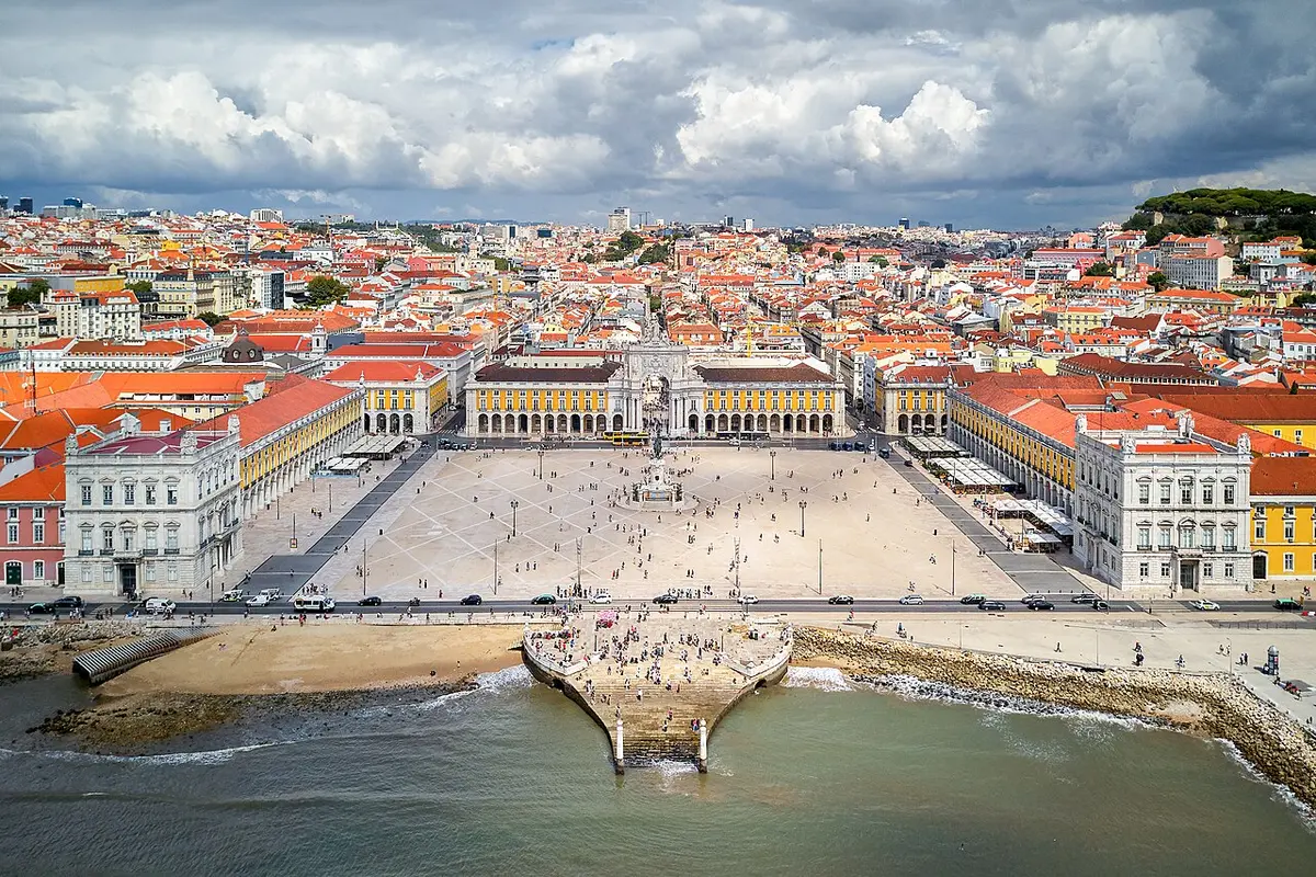 Praça do Comércio from above, the arcaded square open to the Tagus, with the grid of the Baixa behind it