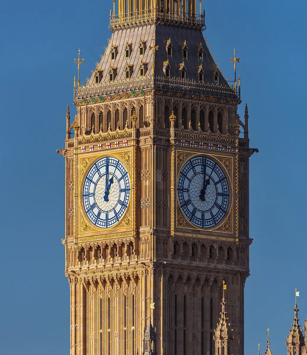 The top of the Elizabeth Tower with two restored clock faces in blue and gold