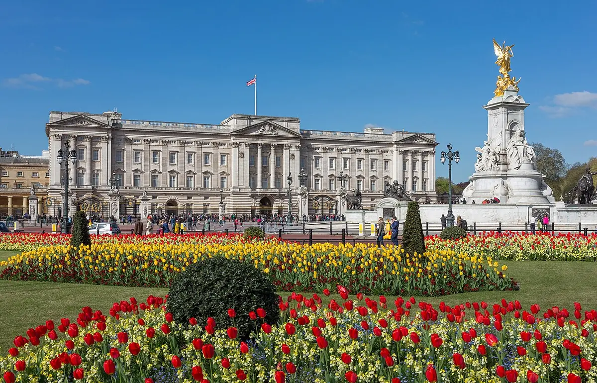 Buckingham Palace and the gilded Victoria Memorial behind beds of red and yellow tulips