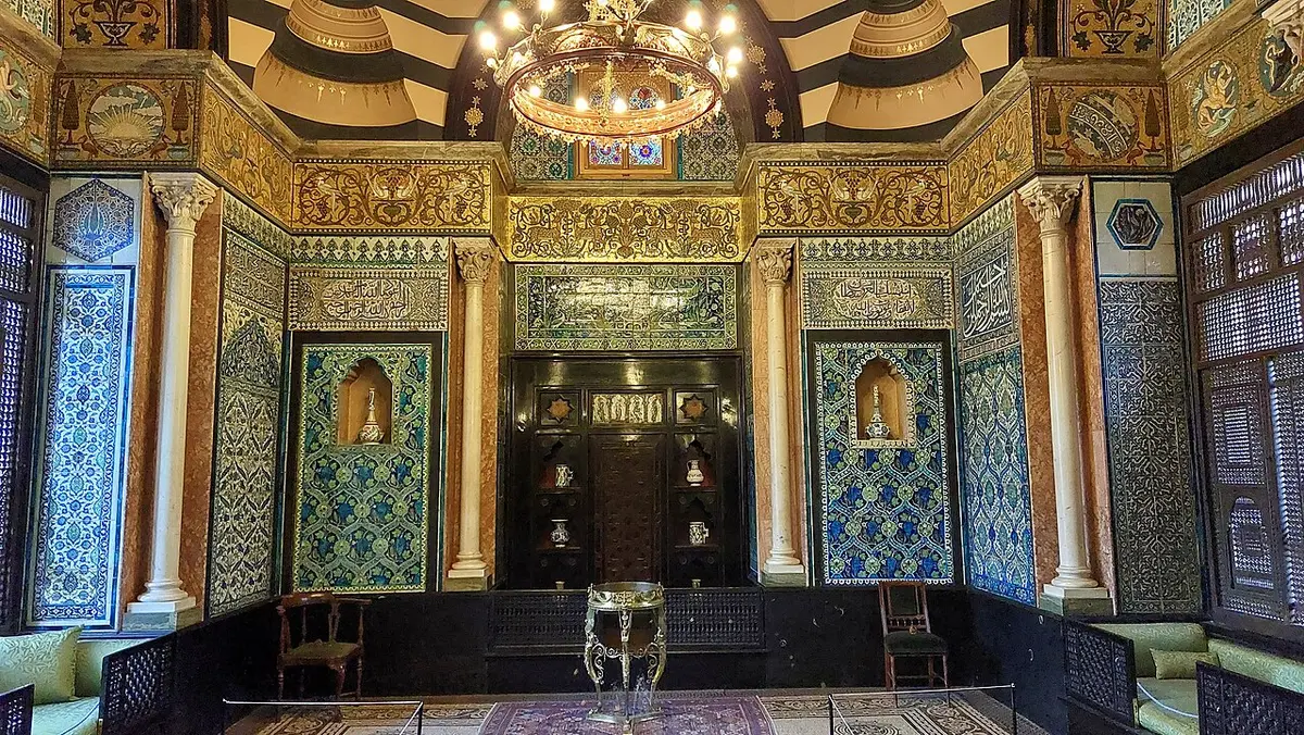 The Arab Hall at Leighton House, its walls covered in blue Islamic tiles under a gilded frieze and chandelier