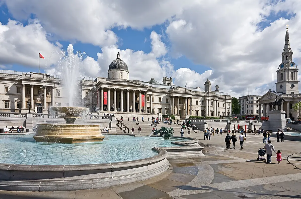 A fountain in Trafalgar Square with the columned front of the National Gallery behind it