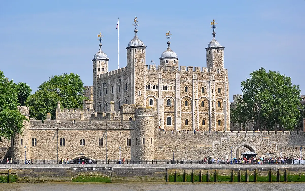 The White Tower of the Tower of London rising above its outer walls by the river