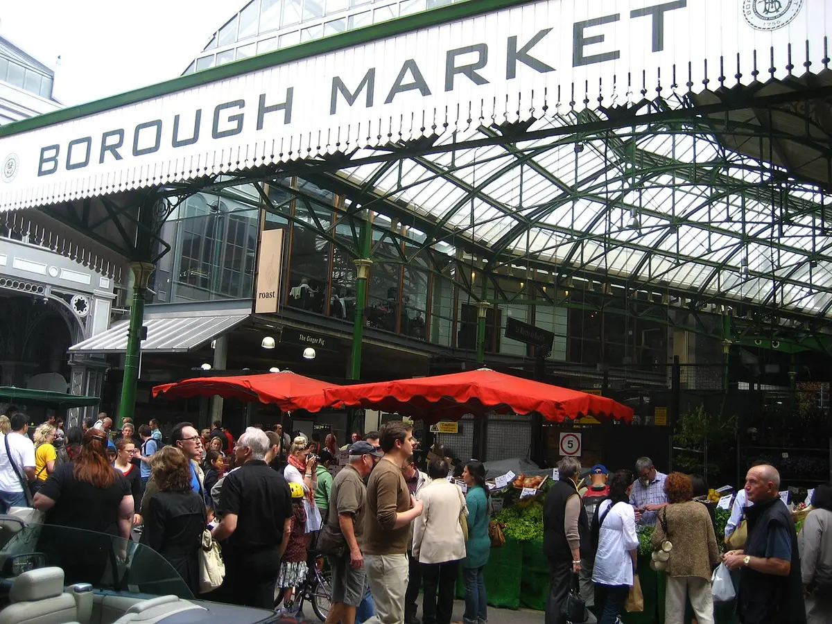 The iron and glass entrance of Borough Market with its name on the arch and shoppers below