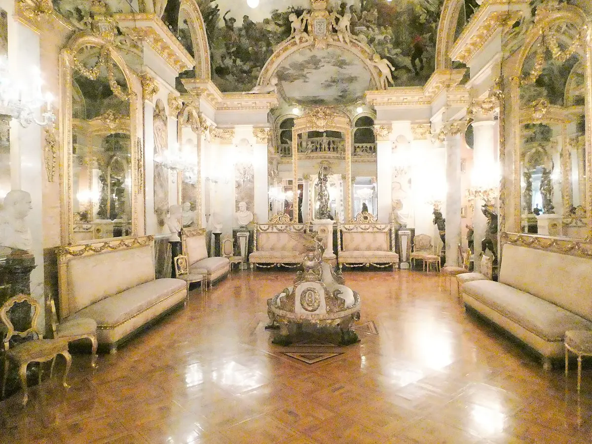 The gilded ballroom of the Cerralbo Museum, with mirrors, a painted ceiling and silk sofas around a polished floor