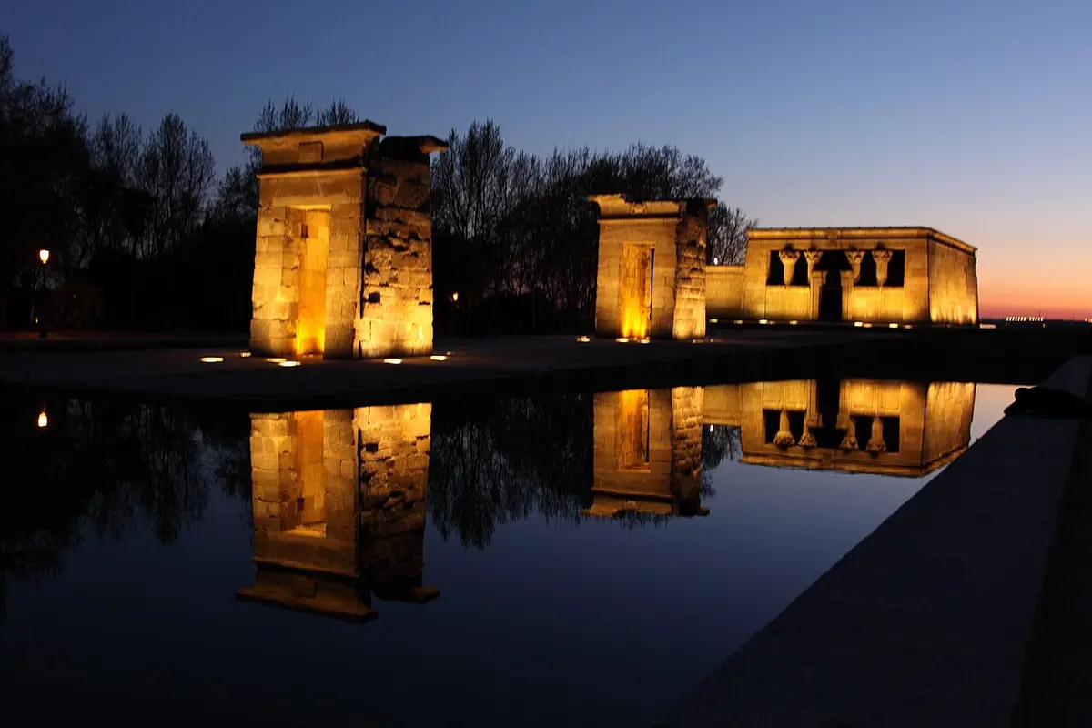 The stone gateways and temple of Debod lit at dusk and reflected in the pool in front of them