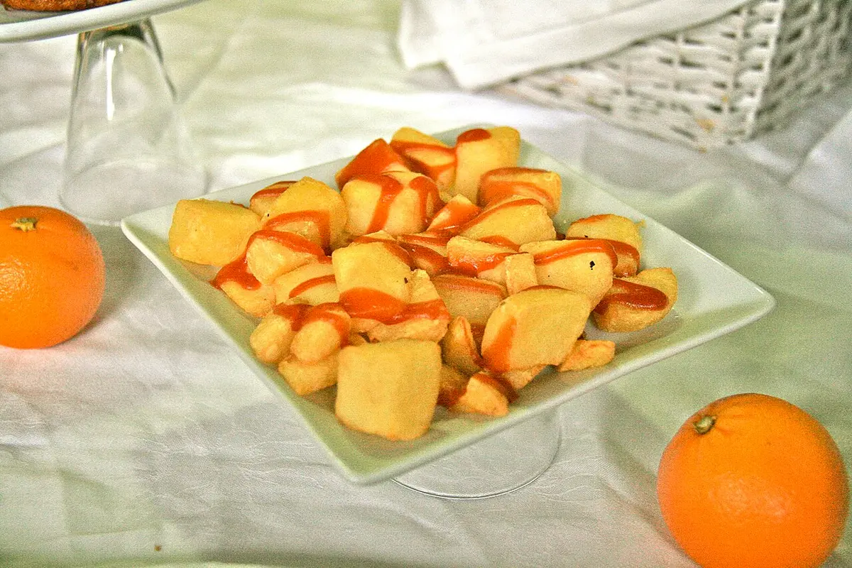 Fried potato cubes with a spicy red sauce on a white plate