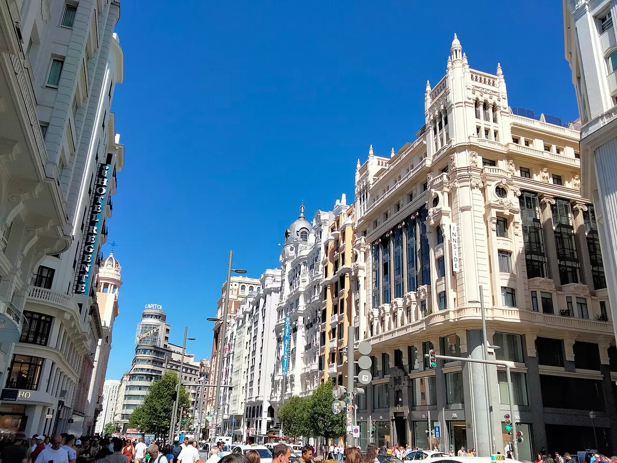 Early 20th-century buildings along Gran Vía under a blue sky, with the curved Capitol building in the distance