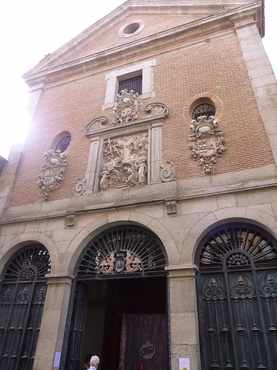 The brick front of the Trinitarian convent church, with a stone relief and three arched iron gates