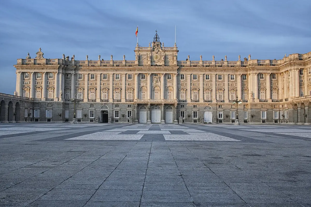 The Royal Palace of Madrid seen across the paved Plaza de la Armería in late afternoon light
