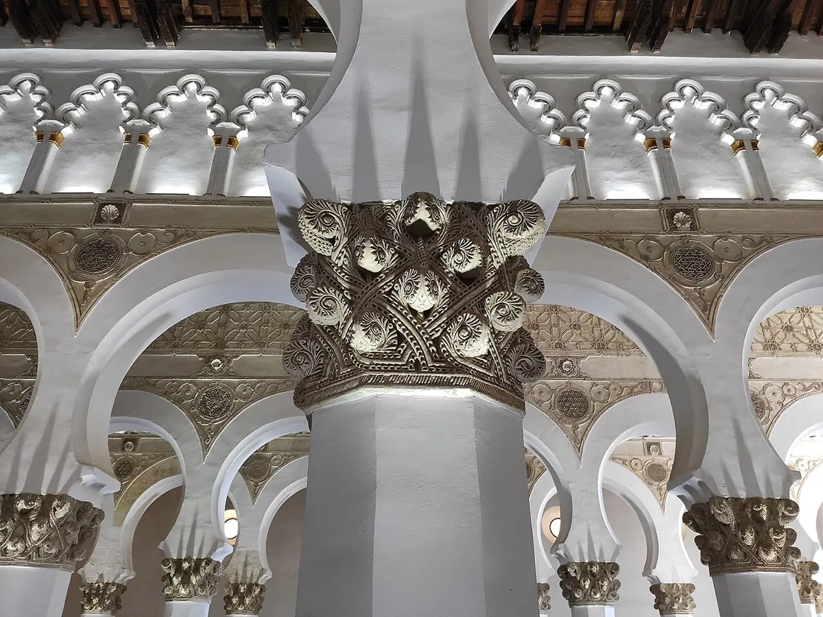 White horseshoe arches on octagonal piers with carved capitals inside Santa María la Blanca