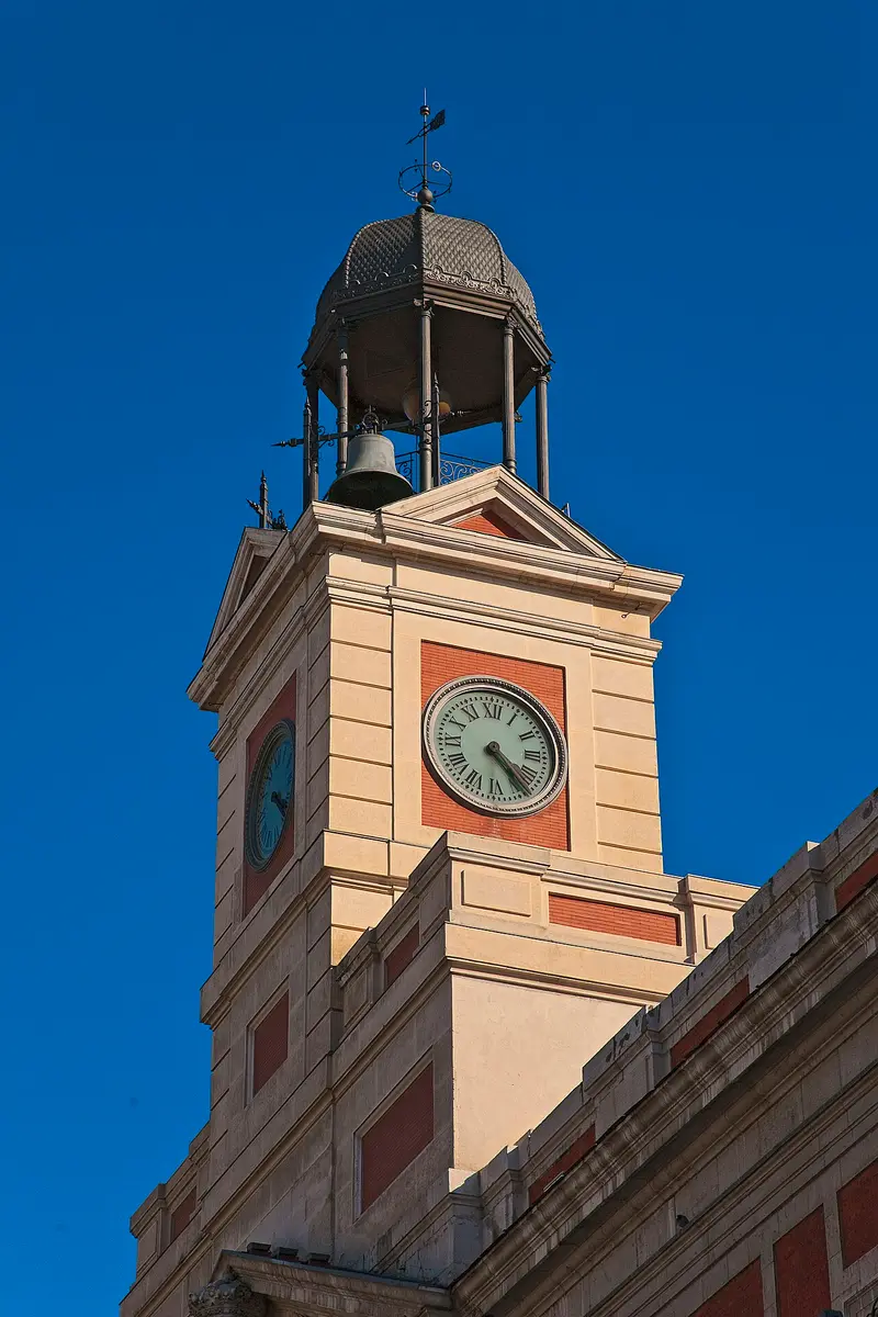 The clock tower of the Real Casa de Correos on Puerta del Sol against a deep blue sky