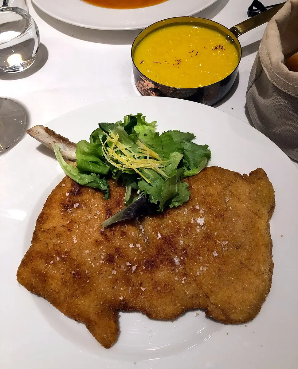 A bone-in breaded veal cutlet with salad leaves