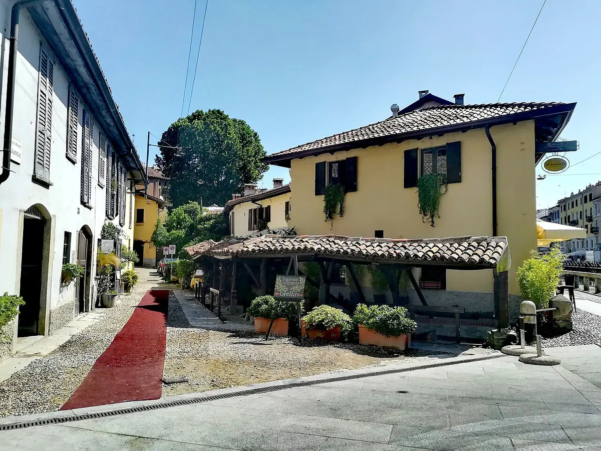 A tiled roof over an old stone washing basin in the Vicolo dei Lavandai, beside a yellow house