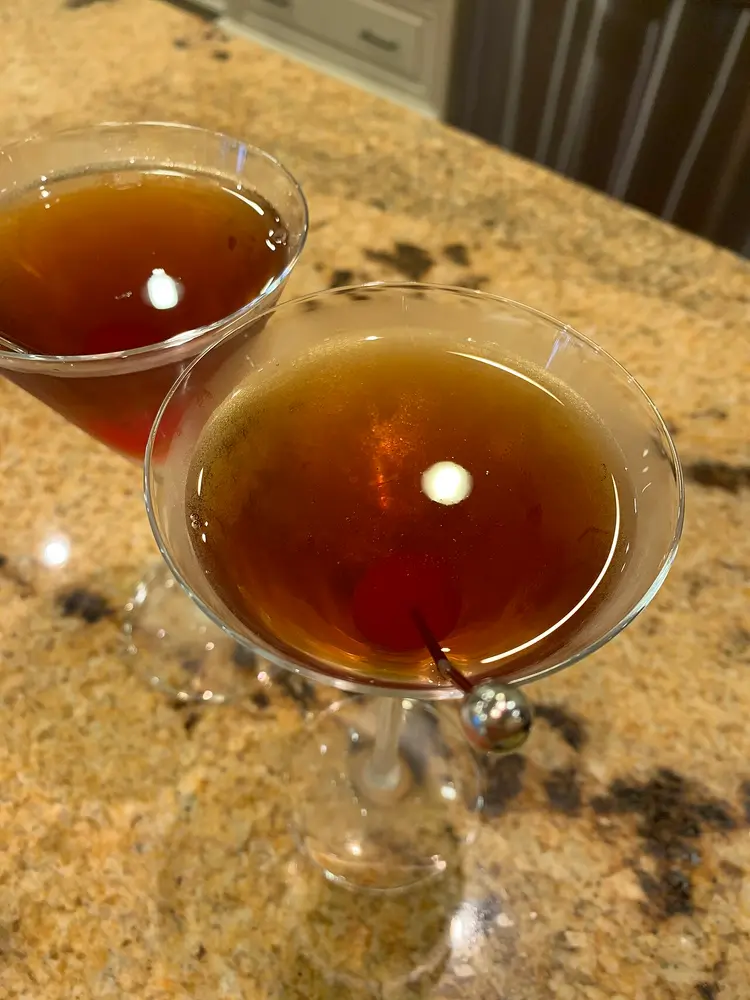 Two Manhattan cocktails in stemmed glasses, each with a cherry, seen from above