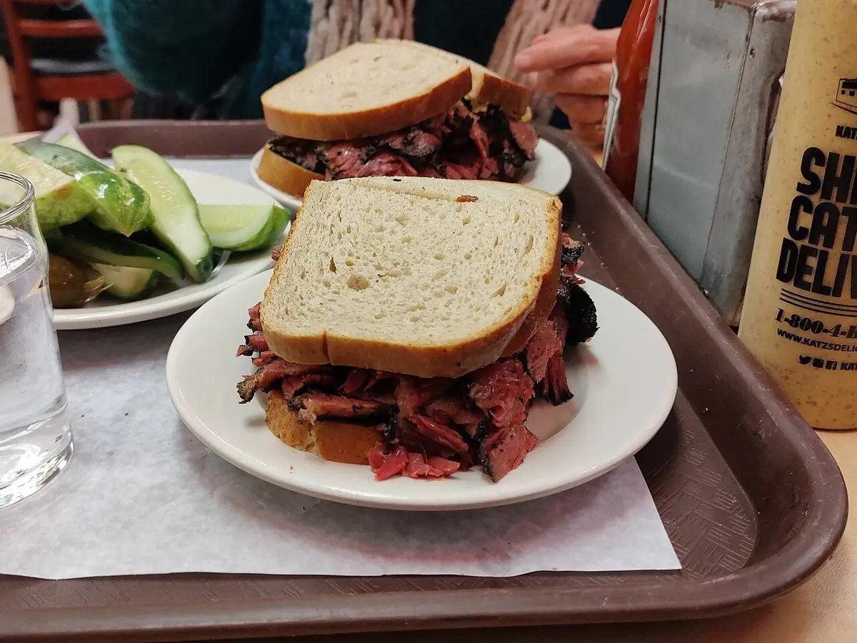 Two pastrami sandwiches on rye with pickles on a tray at Katz’s Delicatessen