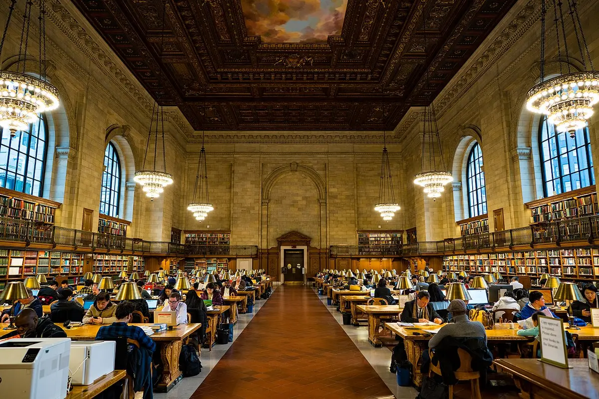 The long Rose Main Reading Room of the New York Public Library, with reading tables, arched windows and a painted ceiling