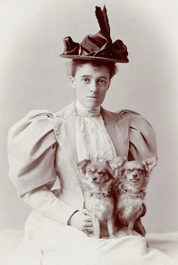 Photograph of the young Edith Wharton in a feathered hat, holding two small dogs