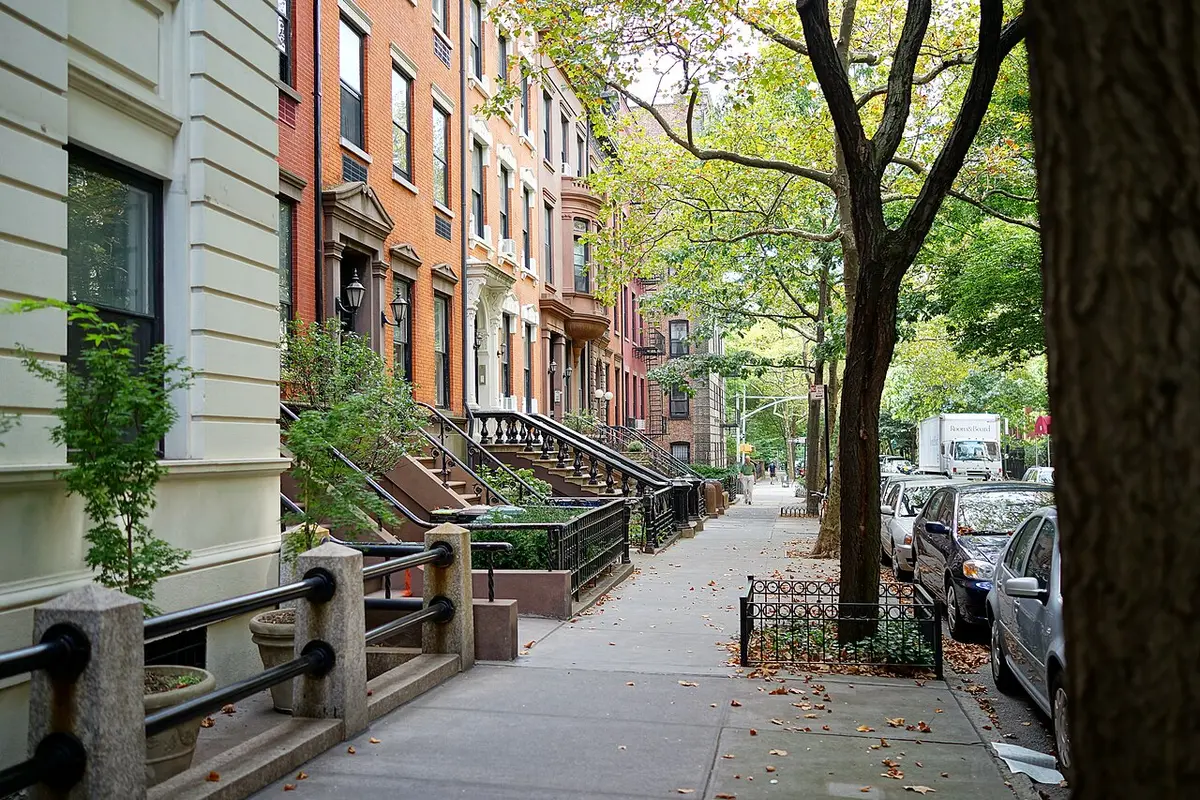A quiet tree-lined street of brick and brownstone row houses with stoops in Brooklyn Heights