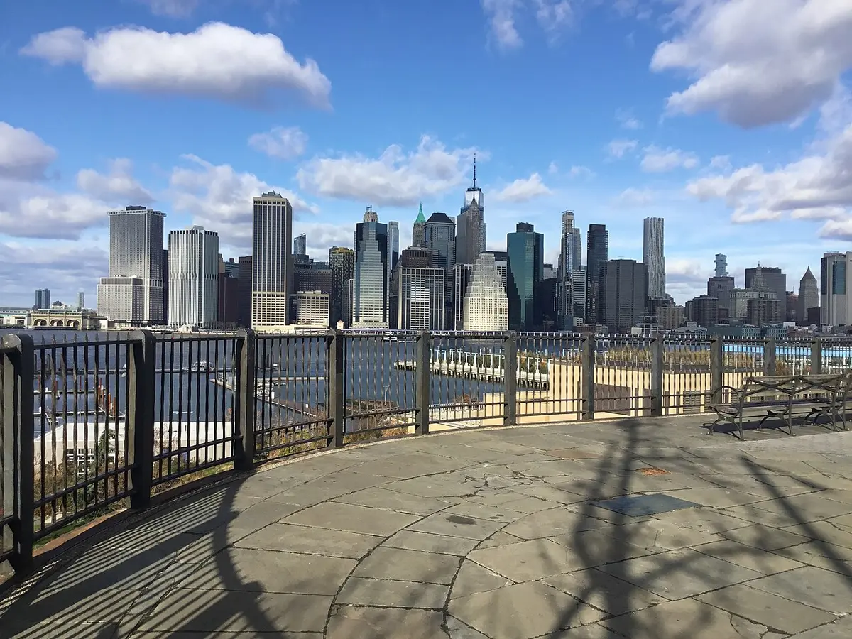 The railing of the Brooklyn Heights Promenade with the towers of Lower Manhattan across the river