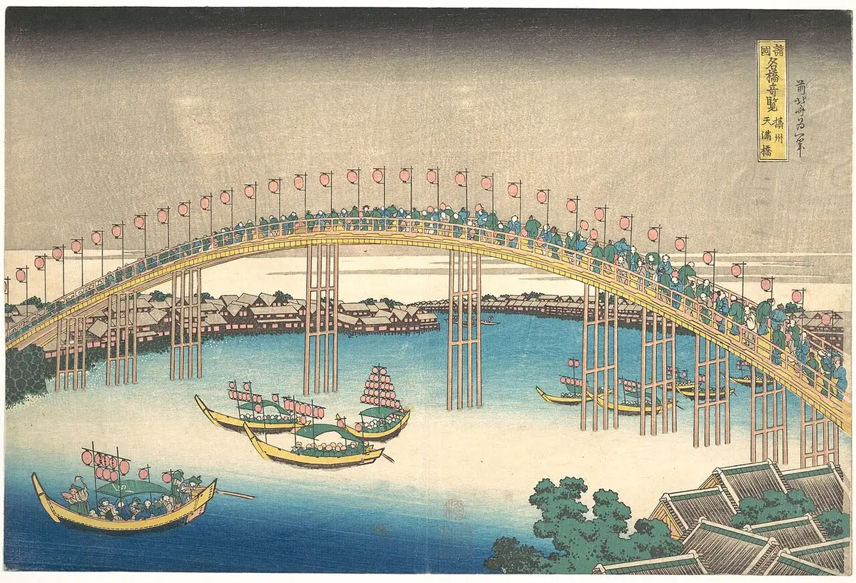 Hokusai print of a long arched bridge lined with banners over a river crowded with festival boats