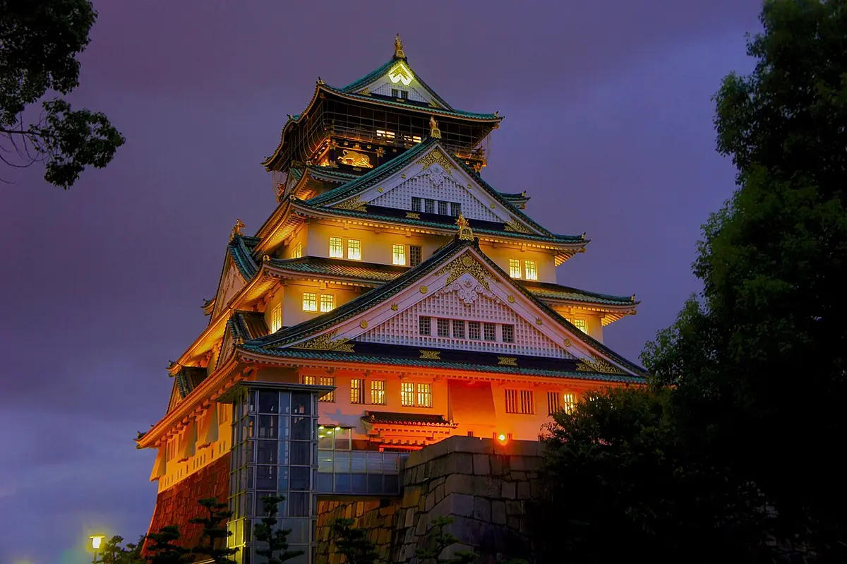 The keep of Osaka Castle lit up at dusk against a deep blue sky