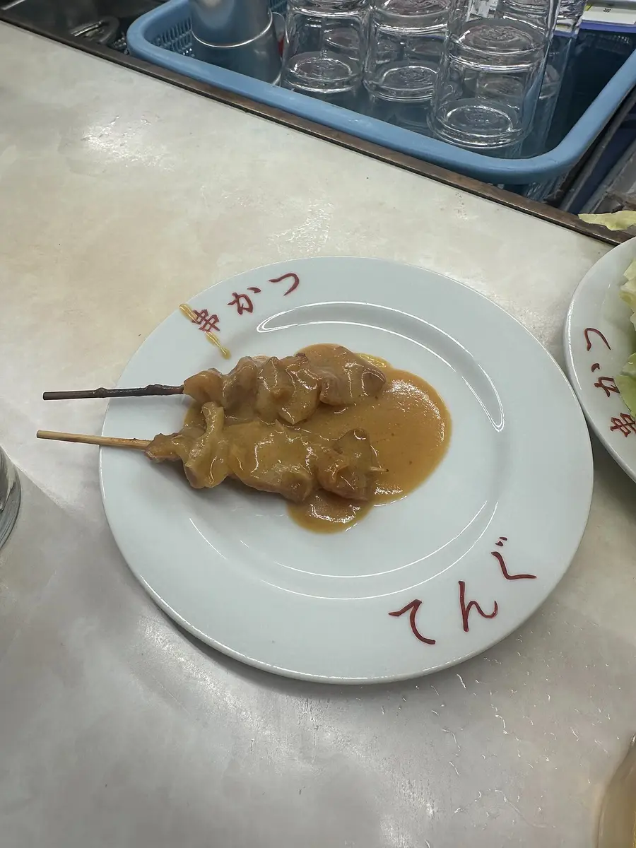 Two skewers of doteyaki, beef sinew stewed in miso, on a white plate
