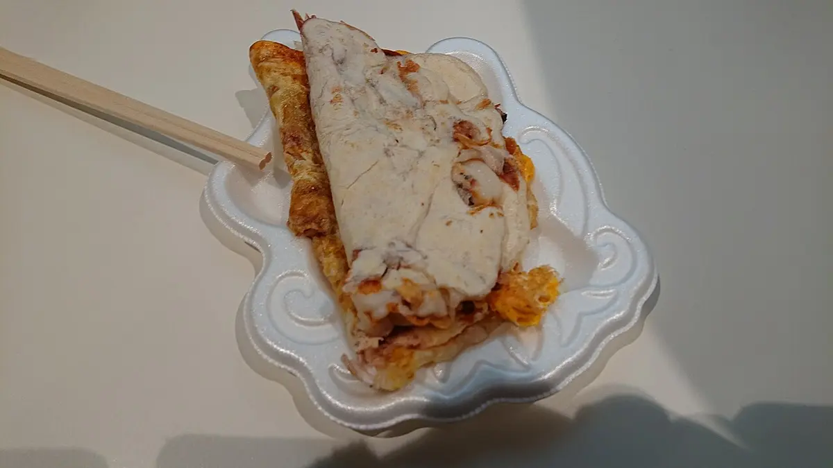 An Osaka-style ikayaki, a folded flour crepe with squid, on a paper tray
