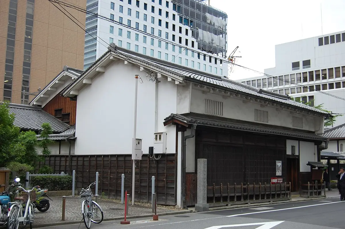 The white plastered front of the Tekijuku, an old merchant house, with office blocks behind