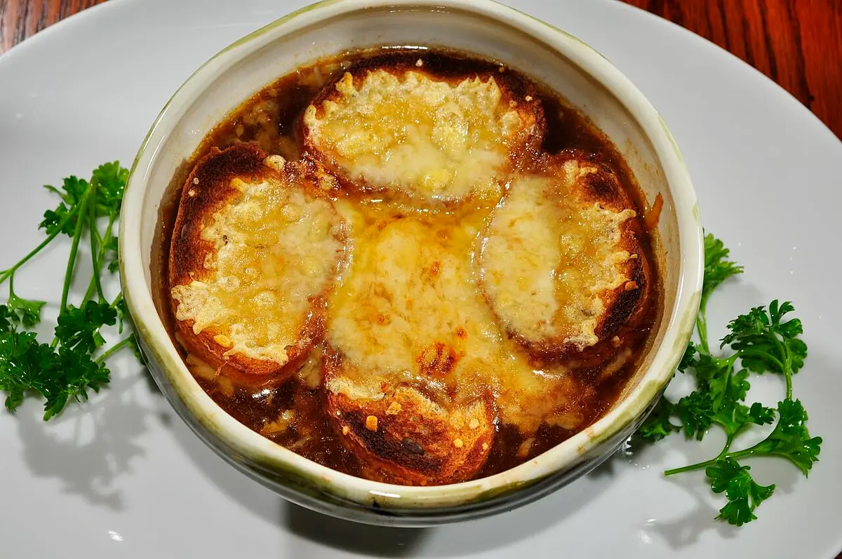 A bowl of onion soup topped with rounds of toasted bread and melted cheese