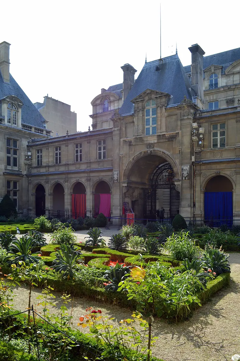 A formal garden with clipped hedges and flowers in the courtyard of the Musée Carnavalet
