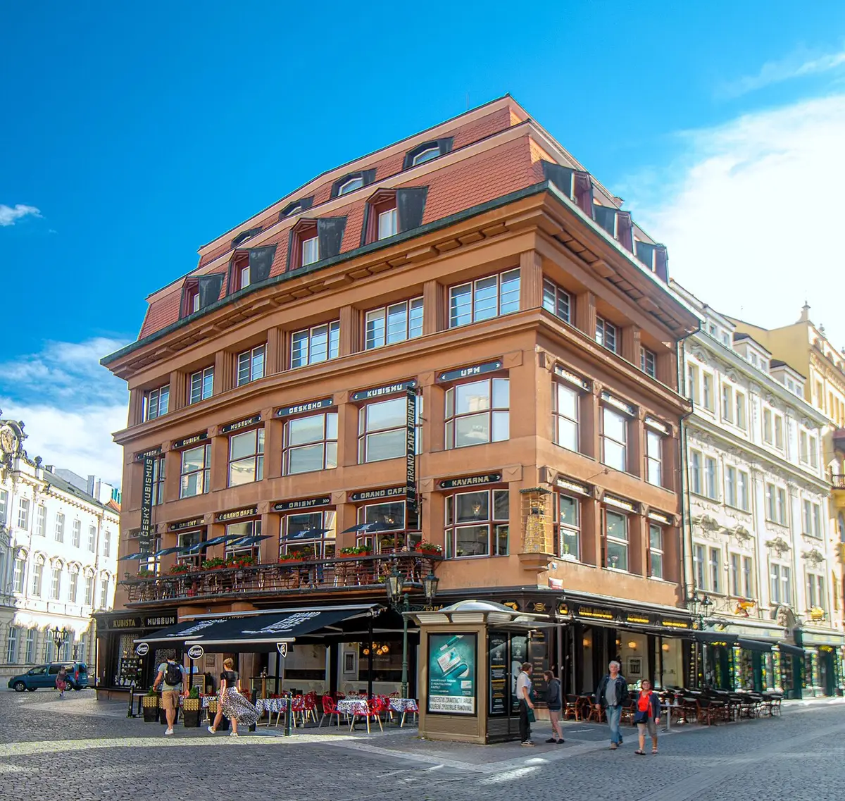 The House of the Black Madonna, a Cubist corner building with angular window frames, under a blue sky