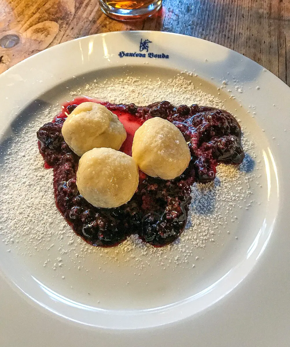 Three fruit dumplings on blueberry sauce, dusted with sugar