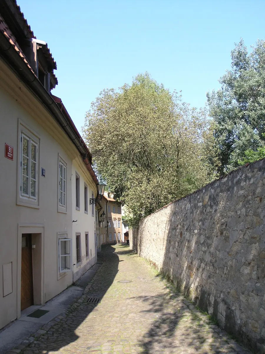 A quiet cobbled lane of low houses beside an old stone wall in Nový Svět, Hradčany