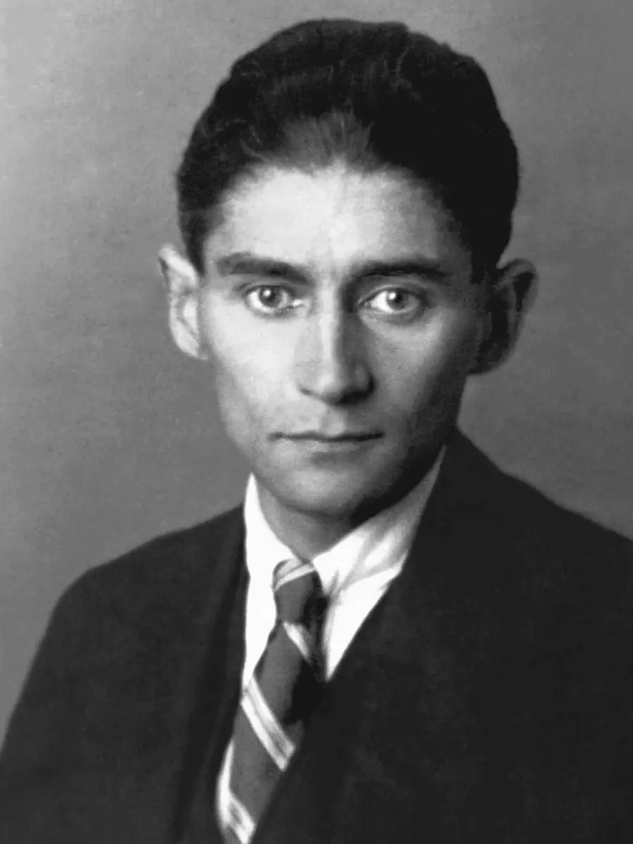 Black and white portrait photograph of Franz Kafka in a dark suit and striped tie