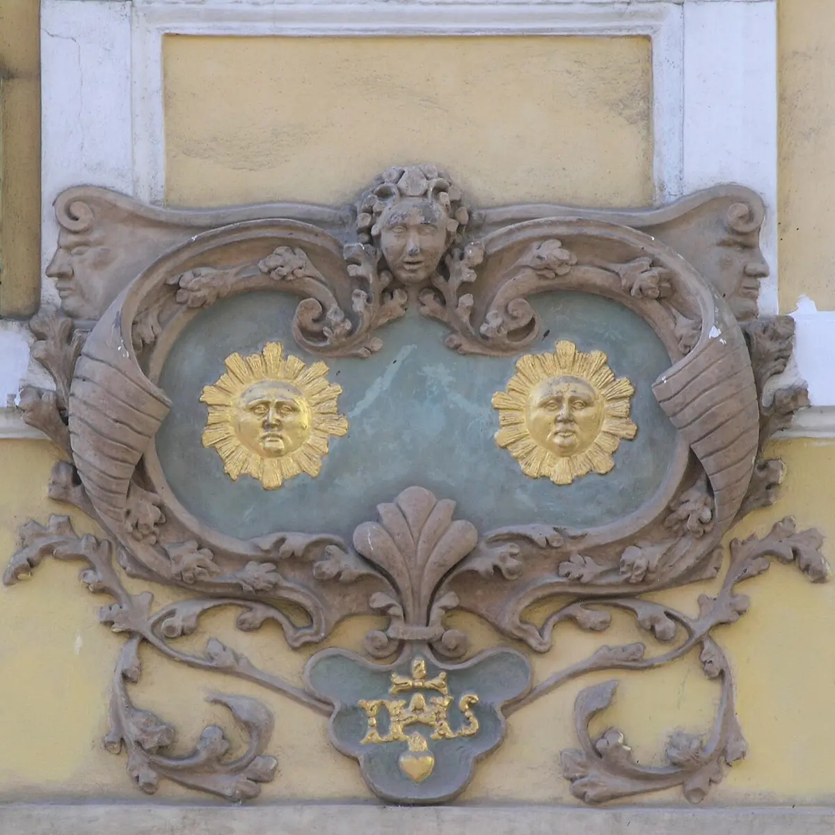 A baroque house sign with two golden suns in a carved frame