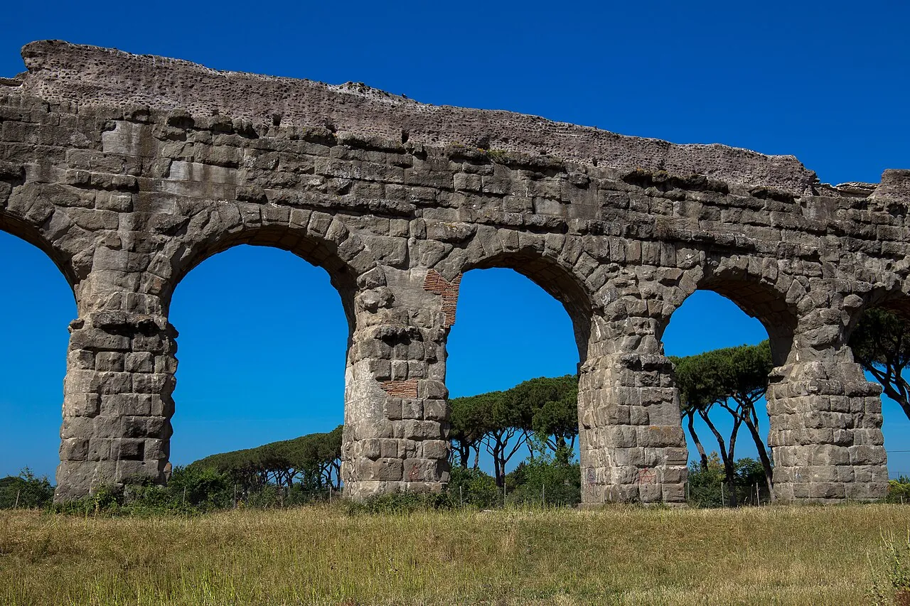 Arches of the Aqua Claudia aqueduct crossing a grassy park