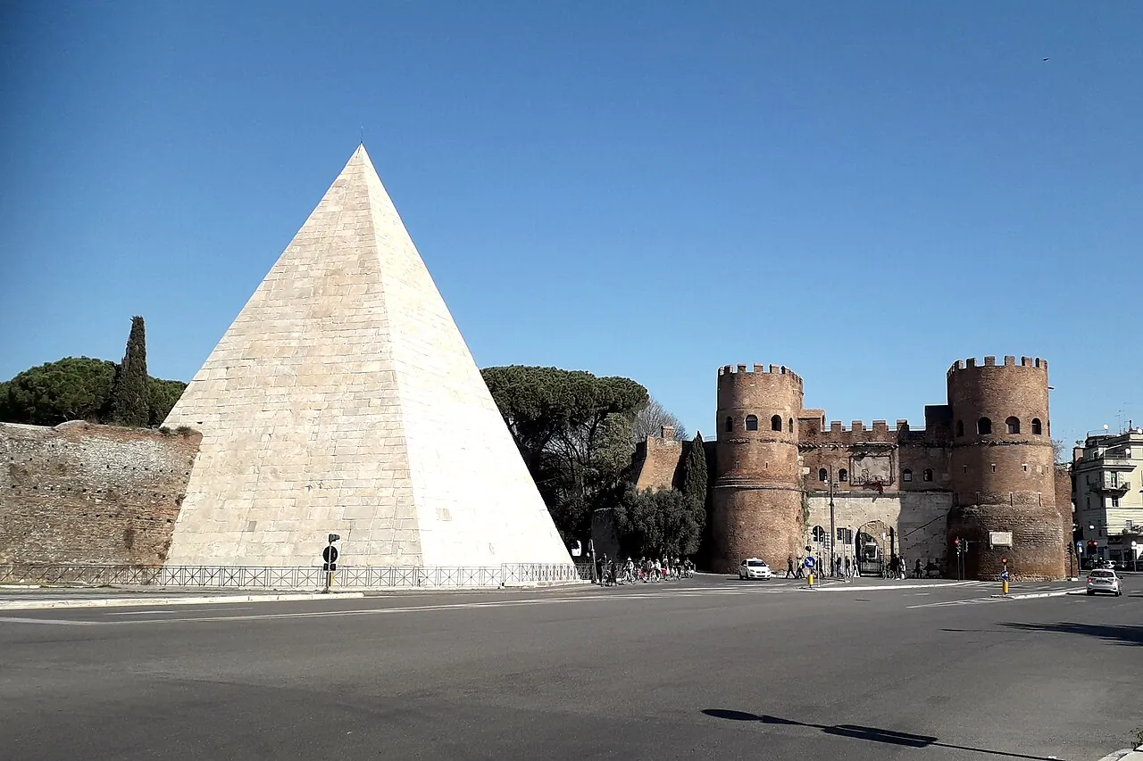 The white marble Pyramid of Cestius next to the towers of the Porta San Paolo gate
