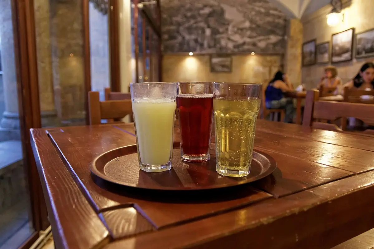 Three glasses of Lagidze lemonade, yellow, red and green, on a tray in a café