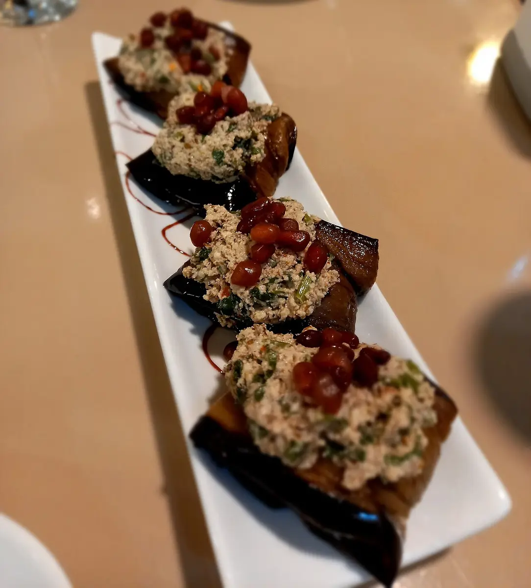 Fried eggplant slices topped with walnut paste and pomegranate seeds