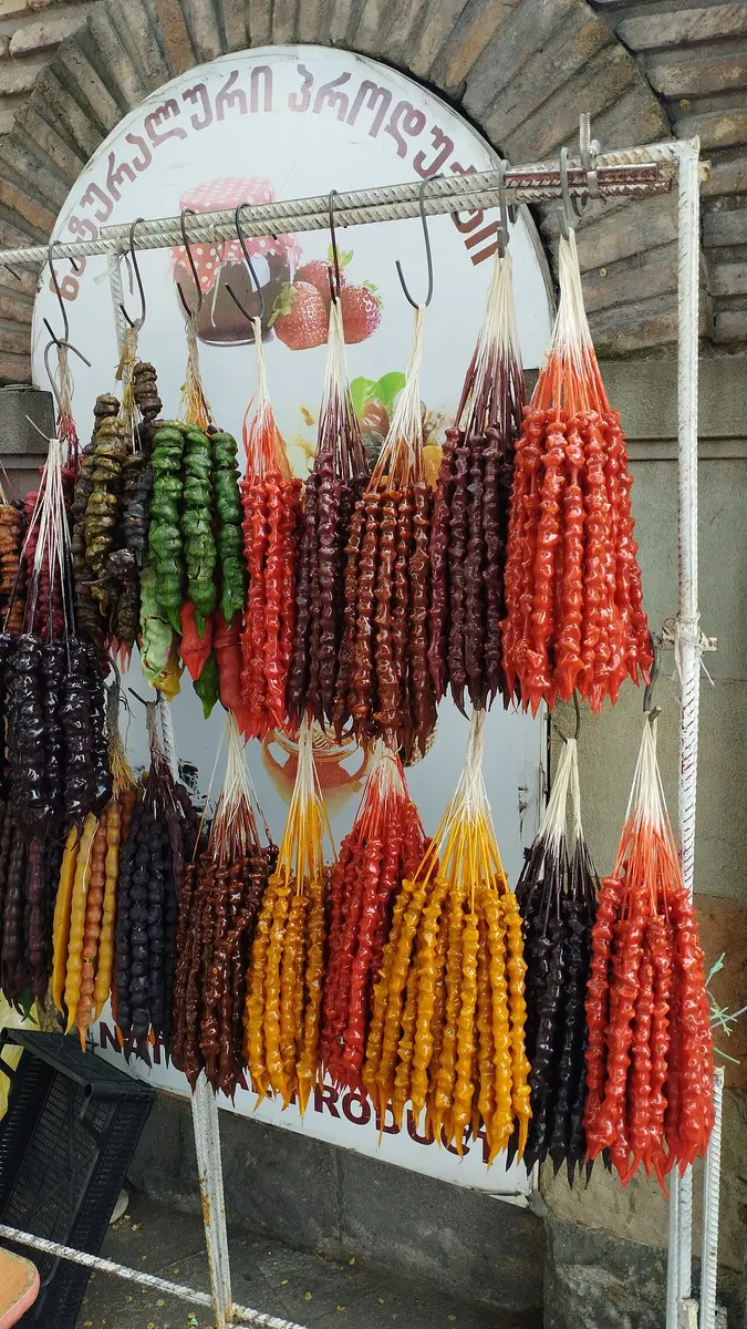 Strings of churchkhela in red, orange and purple hanging at a stall